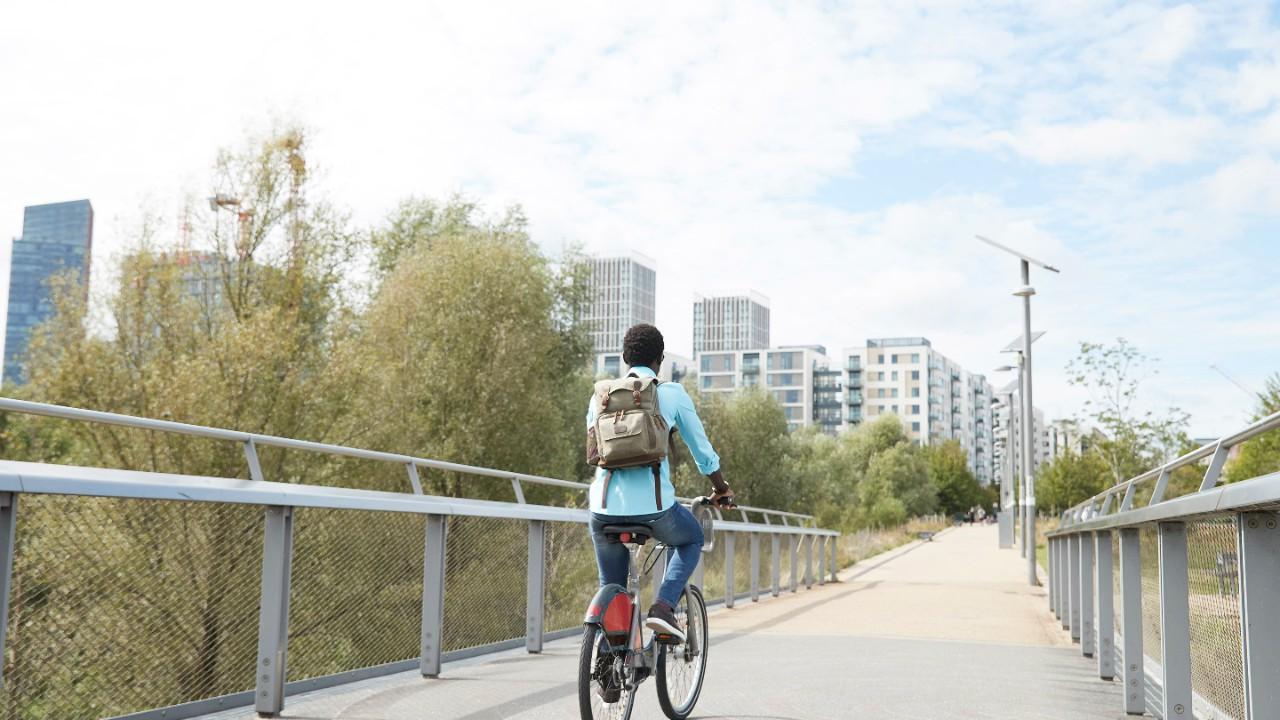 Fille faisant du vélo sur un pont vers une ville.